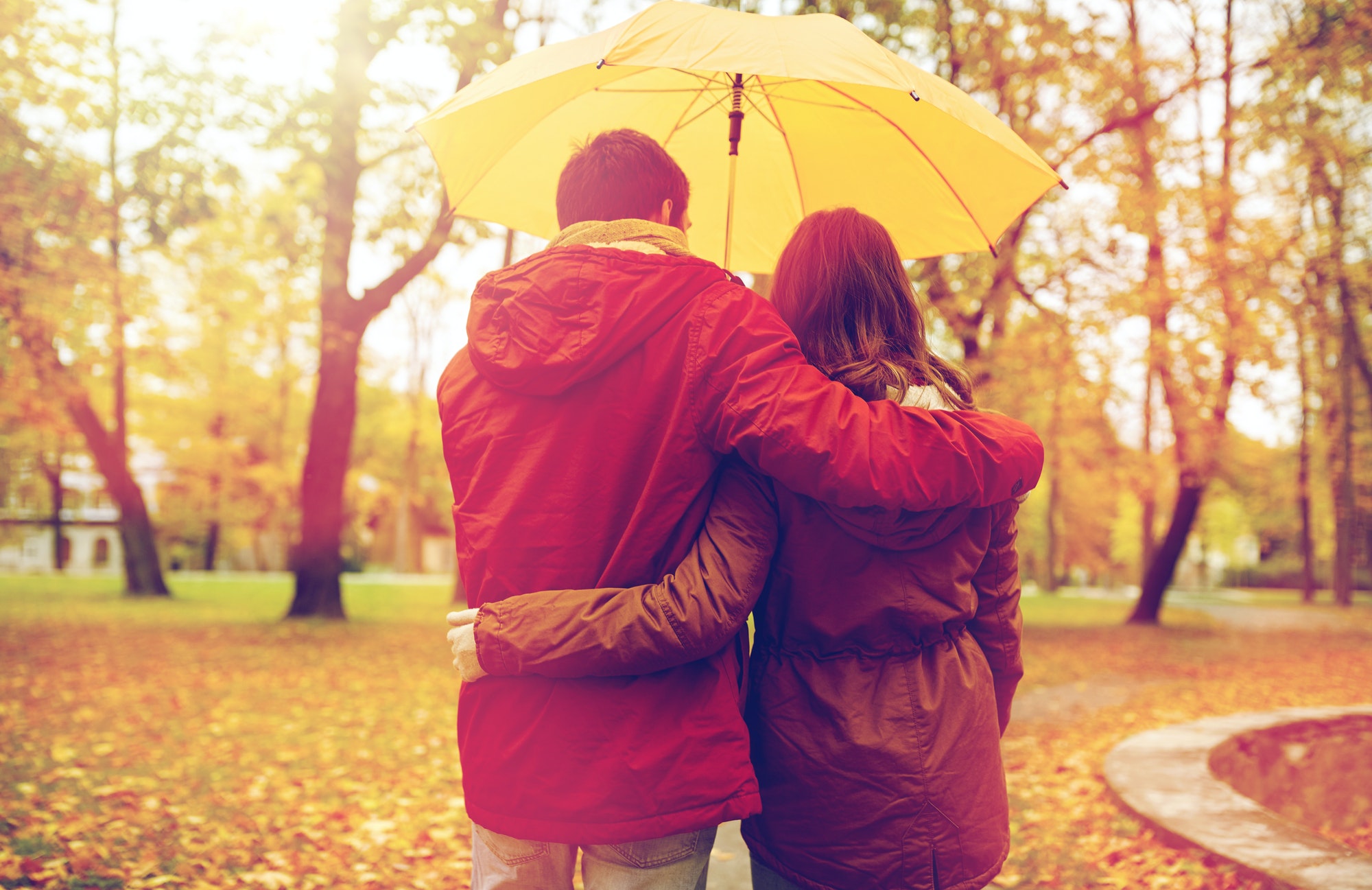 happy couple with umbrella walking in autumn park